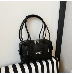 Close-up of matte black leather underarm bag featuring dual zippers and silver turn-lock