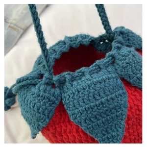 Macro detail of handmade red strawberry knit handbag showing intricate crochet textures