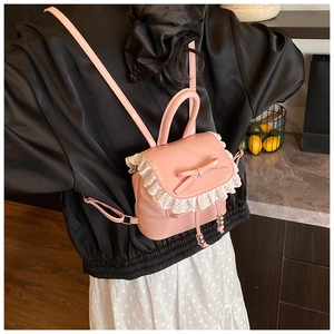 Close-up of a pink ballet-style mini backpack with lace trim and bow on a model