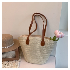 Detail of straw woven tote bag with brown leather straps and pearl decorated beach hat