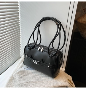 Detail of minimalist black underarm bag with triple zippers and metallic buckle decoration
