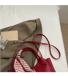 Detail of red crocodile pattern bucket bag with printed silk scarf handle decoration