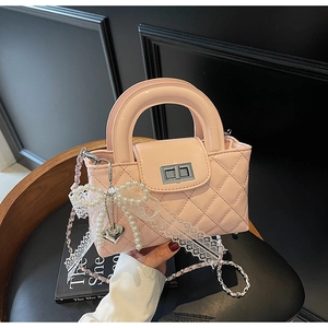 Detail of pink patent leather handbag with quilted pattern and pearl bow charm