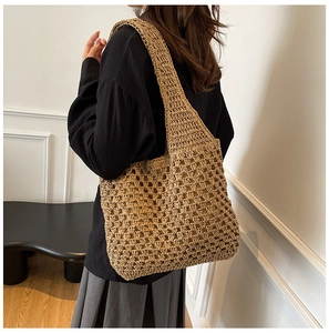Detail of hand-woven hollow straw tote bag showing khaki mesh texture on shoulder