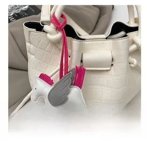 Detailed view of a white leather pegasus bag charm on a crocodile texture bucket bag