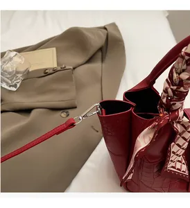 Macro shot of red bucket bag with stone texture, decorative scarf, and silver hardware