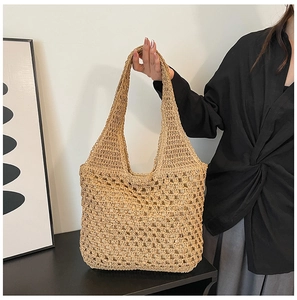 Close-up of hollowed-out crochet straw tote bag with wide shoulder strap and soft lining