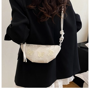 Detaillierte Stickerei von 3D-Schmetterlingen auf einer cremefarbenen Crossbody-Tasche