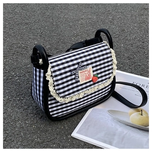 Detail of gingham canvas bag featuring lace edges, rabbit patch, and strawberry charm