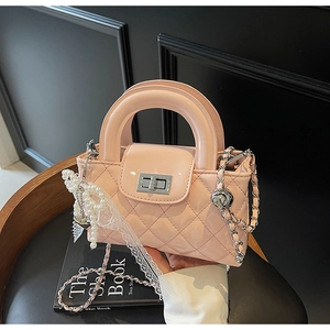 Detail of pink quilted patent leather bag with pearl bow and silver twist lock