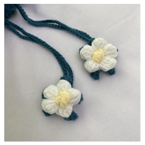 Detail view of handmade crochet flower charm with soft white petals and yellow center