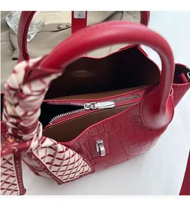 Detail of red croc-embossed bucket bag with silk scarf handle and internal zipper pocket