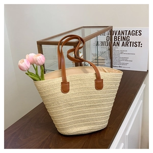 Close-up of woven straw tote bag with brown faux leather handles for beach vacation