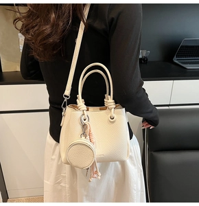 Detail of lychee pattern leather bucket bag with braided handle and round coin purse