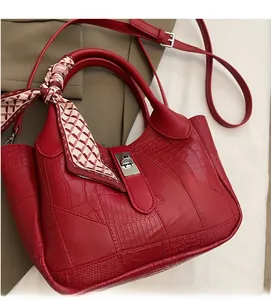 Detail of red faux leather bucket bag with stone pattern and decorative silk scarf