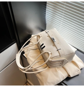 Detail of cream leather shoulder bag featuring side triple zippers and textured finish