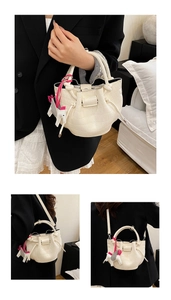 Macro detail of cream bucket bag with crocodile texture and horse charm accent