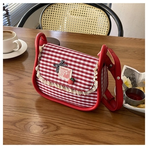 Close-up of red gingham canvas bag with lace trim, strawberry charm and bow detail