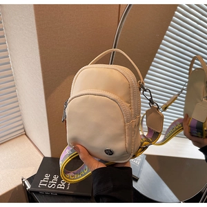 Détail d'un sac bandoulière beige en nylon avec double zip et sangle large colorée