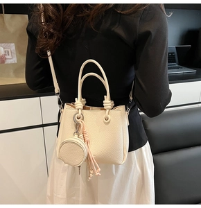 Detail view of cream lychee texture bucket bag with round coin purse on a model