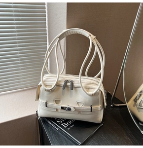 Close-up of cream leather underarm bag with double metal zippers and buckle details