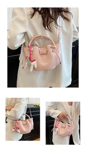 Close-up of pink faux crocodile skin texture and leather Pegasus charm on crossbody bag