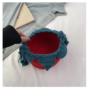 Close-up of handmade knit tomato bag showing red crochet texture and green leaf detail