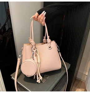 Detail of pink lychee texture bucket bag with knotted handles and round coin purse charm