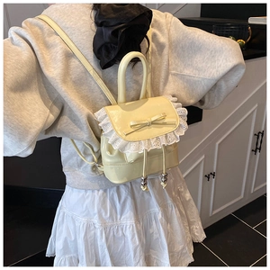 Detail view of mini cream yellow backpack with white lace trim and bowknot design