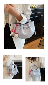Detail of light blue bucket bag with crocodile texture and horse charm accessory