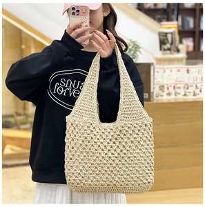 Close-up of cream white hollow out crochet woven straw shoulder bag in casual setting
