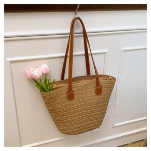 Detail of woven straw tote bag with brown leather straps and smooth fabric lining