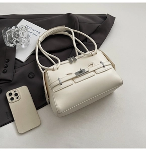 Detailed close-up of cream leather shoulder bag with metallic twist lock and dual handles