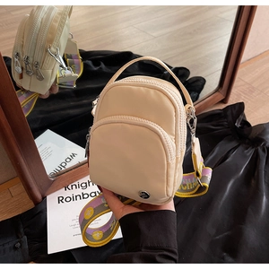 Détail du sac beige à trois compartiments zippés et large bandoulière colorée tissée