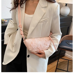 Detail einer rosa Umhängetasche aus Spitzenstoff mit feiner Schmetterlingsstickerei