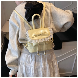 Detail of light yellow ballet style backpack with white lace and ribbon bow decoration