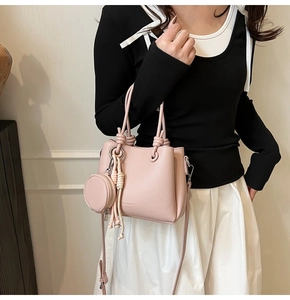 Pink lychee grain bucket bag with knotted handle and round pendant shown on model