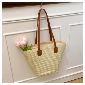 Detail of hand-woven straw beach bag with premium brown leather straps and fine texture