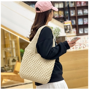 Detail of cream handmade crochet shoulder bag with hollow knit patterns for beach vacations