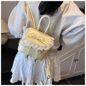 Detail of cream balletcore backpack featuring lace trim, bow accent and glossy finish