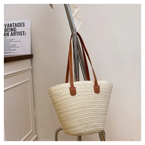 Detail of handwoven cream tote bag with contrast brown leather handles on a rack