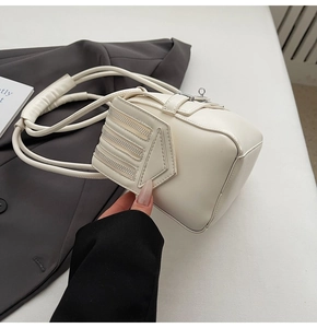 Detail view of cream white box shoulder bag with triple zipper accents on a gray blazer