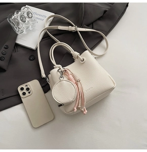 Detailed shot of white lychee leather bucket bag with a round coin purse charm