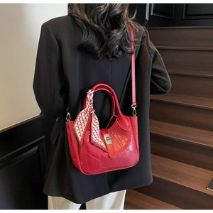 Detail of red croc-effect bucket bag with silk scarf on handle and silver lock