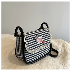 Detail of checkered canvas bag with lace trim, bunny patch and strawberry charm accessory