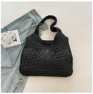 Close-up of black woven beach bag with floral hollow patterns and refined straw texture