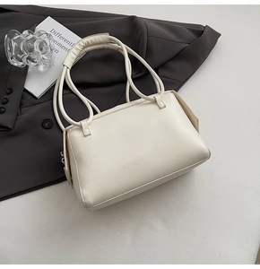 Detail shot of cream white rectangular shoulder bag featuring dual padded handles and soft faux leather