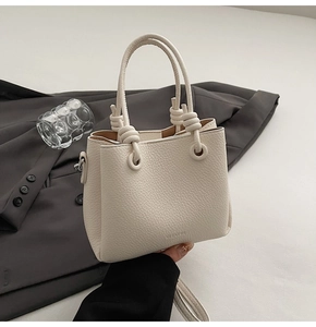 Detail of lychee pattern cream leather bucket bag with knot handle and clean texture