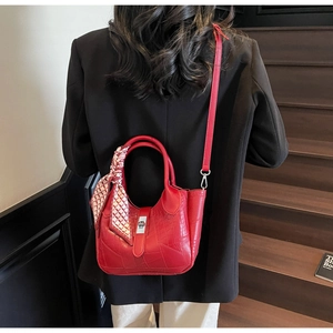 Detail of red crocodile pattern bucket bag with silk scarf on handle and metal lock