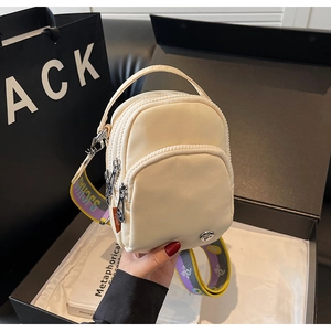 Détail du petit sac bandoulière en nylon beige avec trois zips et sangle jacquard